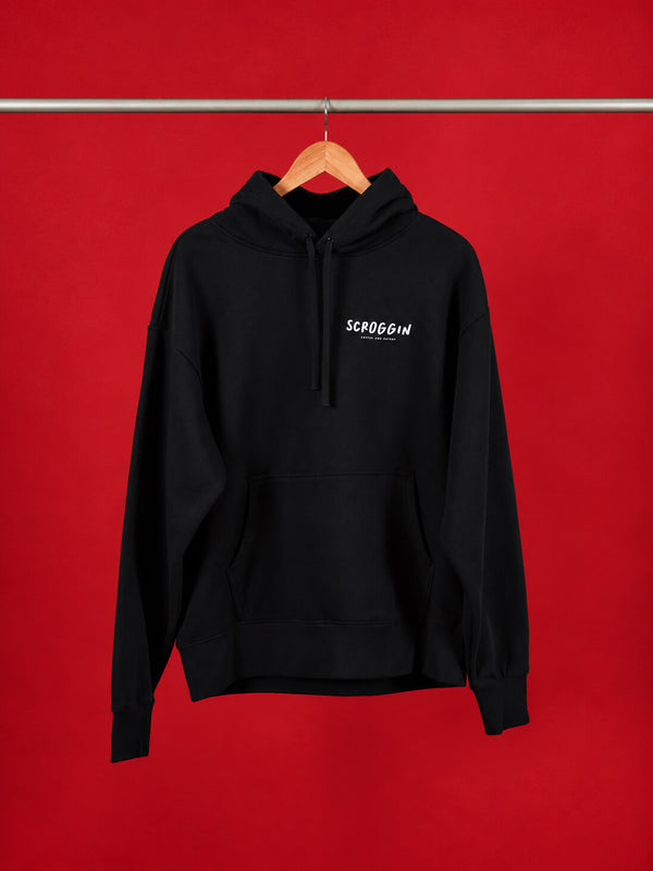 A black pullover hoodie with a white 'SCROGGIN' text logo on the left chest, hanging on a wooden hanger from a metal rod against a solid red background.